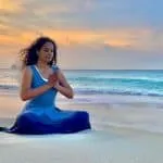 a woman practicing yoga on the beach