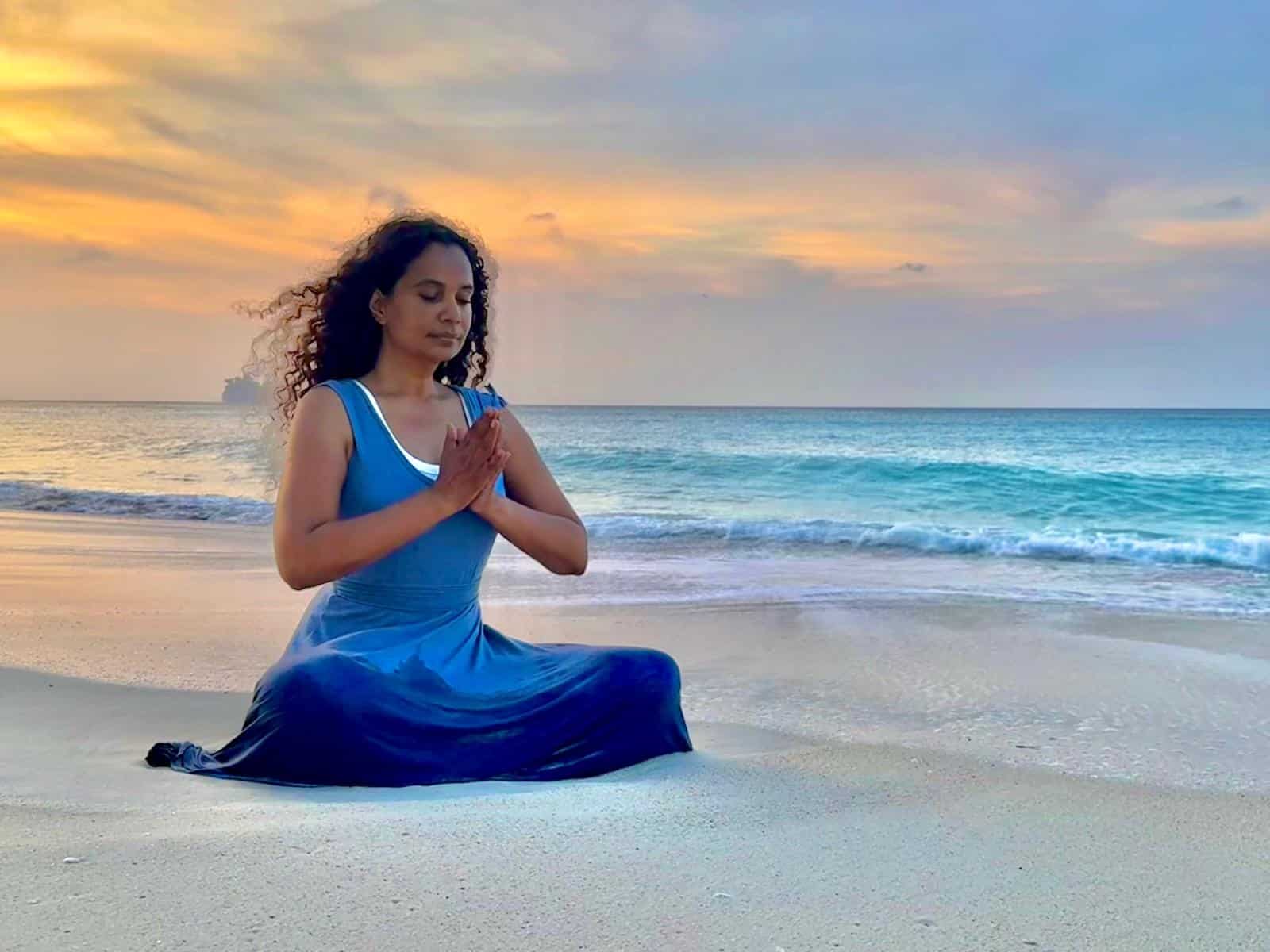 a woman practicing yoga on the beach